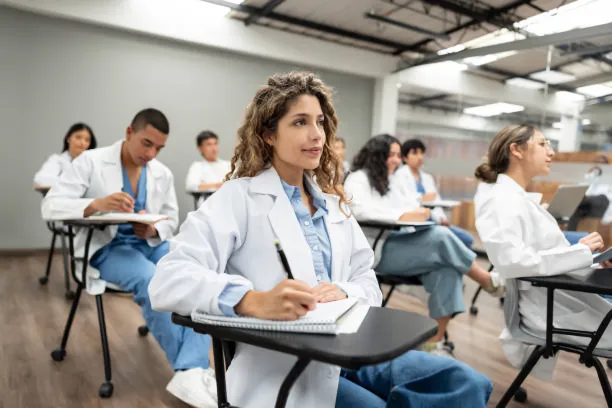 Estudiantes en aula de clases vistiendo batas médicas